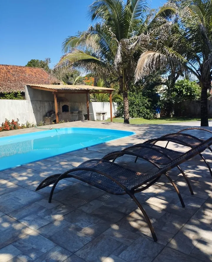 Piscina de sete metros da Casa de Praia Saquarema, com pérgola e espreguiçadeiras